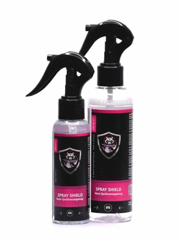 dve priehľadné fľaštičky rôznej veľkosti s rozprašovačom obsahujúce prípravok nano keramická ochrana karosérie vozidla Spray Shield, ktorý je taktiež prieľadnej farby s etiketou a logom autokozmetiky Racoon Cleaning Products