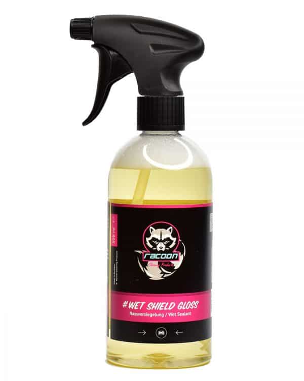 priehľadná fľaša s rozprašovačom obsahujúca žltú číru tekutinu, prípravok určený ako tekutý vosk pri umývaní automobilov Wet Shield Gloss, s etiketou a logom autokozmetiky Racoon Cleaning Products