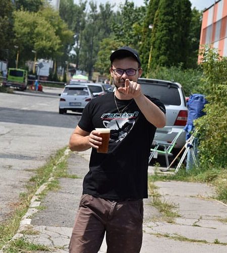 prichádzajúci pozitívne naladený muž držiaci pivo v ruke je odetý do trička s logom Racoon